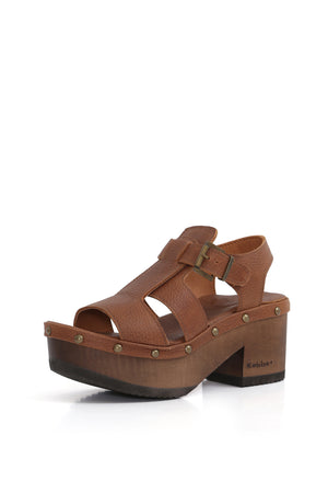 Kebba BUA Bali Texas Tostado, sandalia tipo zueco de cuero liso. Planta artesanal BUA de 8 cm en madera nativa con hebilla metálica. Imagen tres cuartos sobre fondo blanco. Piezas únicas en colecciones limitadas. Hecho a mano en Villarrica. Kebba: tradición y herencia en tus manos