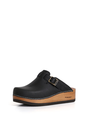 Zuecos de cuero Kebba Riemen Texas Negro, diseño tradicional con ajuste en el empeine. Planta anatómica de madera Tepa de 5 cm. Imagen tres cuartos sobre fondo blanco. Piezas únicas en colecciones limitadas. Hecho a mano en Villarrica. Kebba: tradición y herencia en tus mano