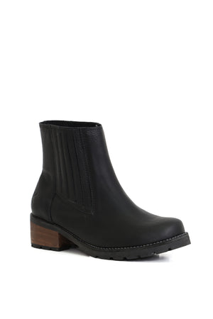 Botín negro Simonita Sancho, confeccionado en cuero liso Texas con elásticos laterales. Imagen frontal sobre fondo blanco. Planta Simonita de 5 cm de altura con forro y plantilla de cuero. Hecho a mano en Villarrica. Kebba: tradición y herencia en tus manos