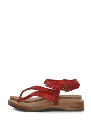 sandalia roja de dedo con tachas y hebilla, vista lateral; planta DK anatómica 3,5 cm en madera tepa. zapatos anatómicos