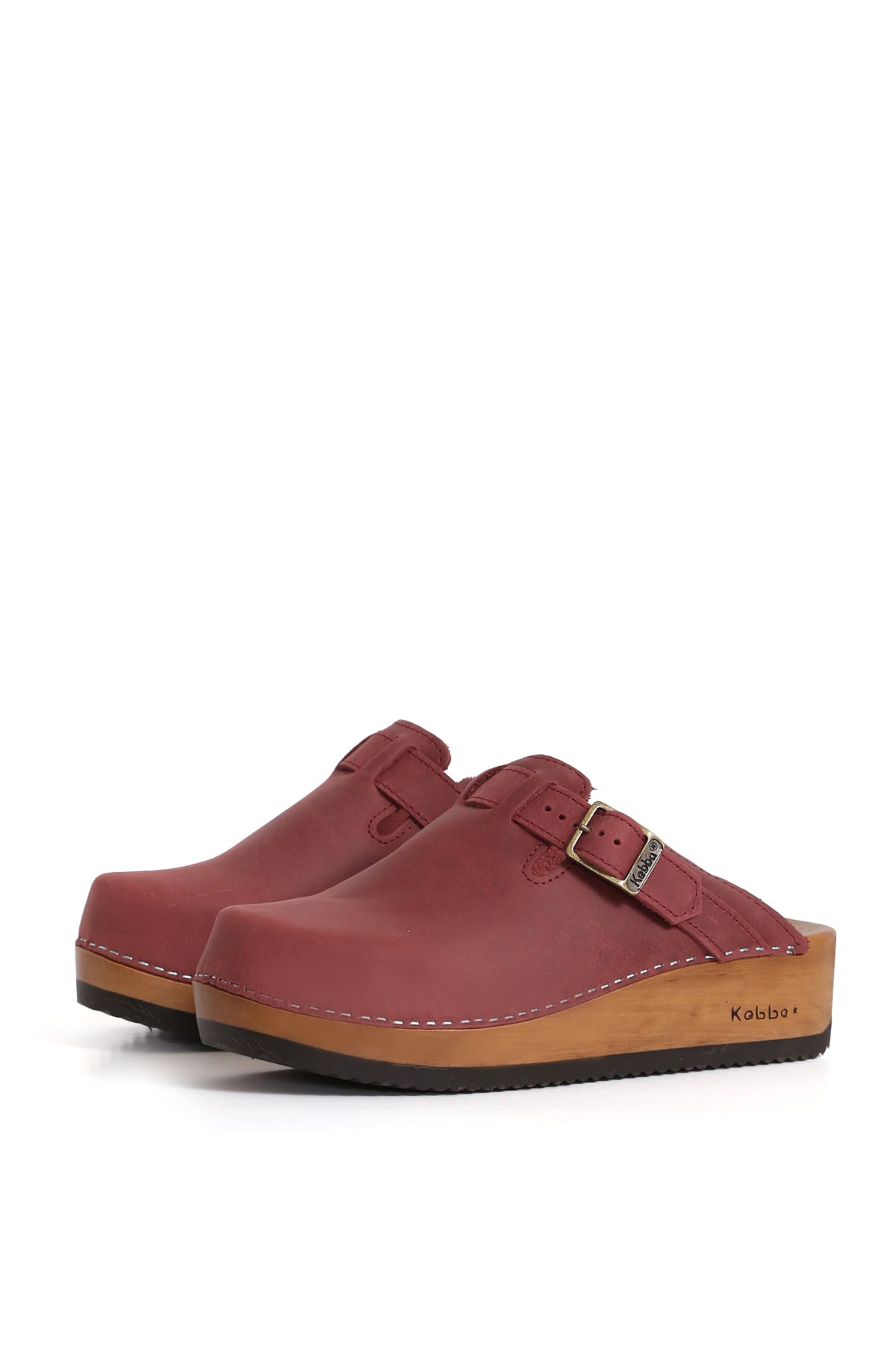 Modelo Kebba zueco tradicional en cuero West guinda, opaco y rústico. Planta anatómica de madera de 5 cm para máxima comodidad. Imagen lateral sobre fondo blanco. Piezas únicas en colecciones limitadas. Hecho a mano en Villarrica. Kebba: tradición y herencia en tus manos