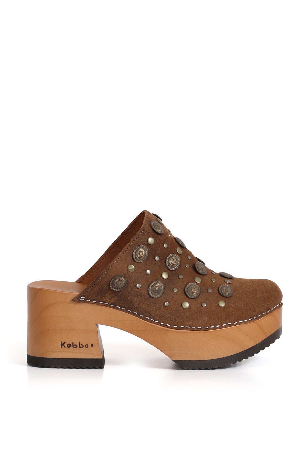 Modelo Pájaro Pastora Renobuk Tostado de Kebba, sandalia tipo zueco en cuero renobuk con tachas. Planta de madera álamo de 8 cm y forro de cuero caramelo. Imagen trasera sobre fondo blanco. Piezas únicas en colecciones limitadas. Hecho a mano en Villarrica. Kebba: tradición y herencia en tus manos