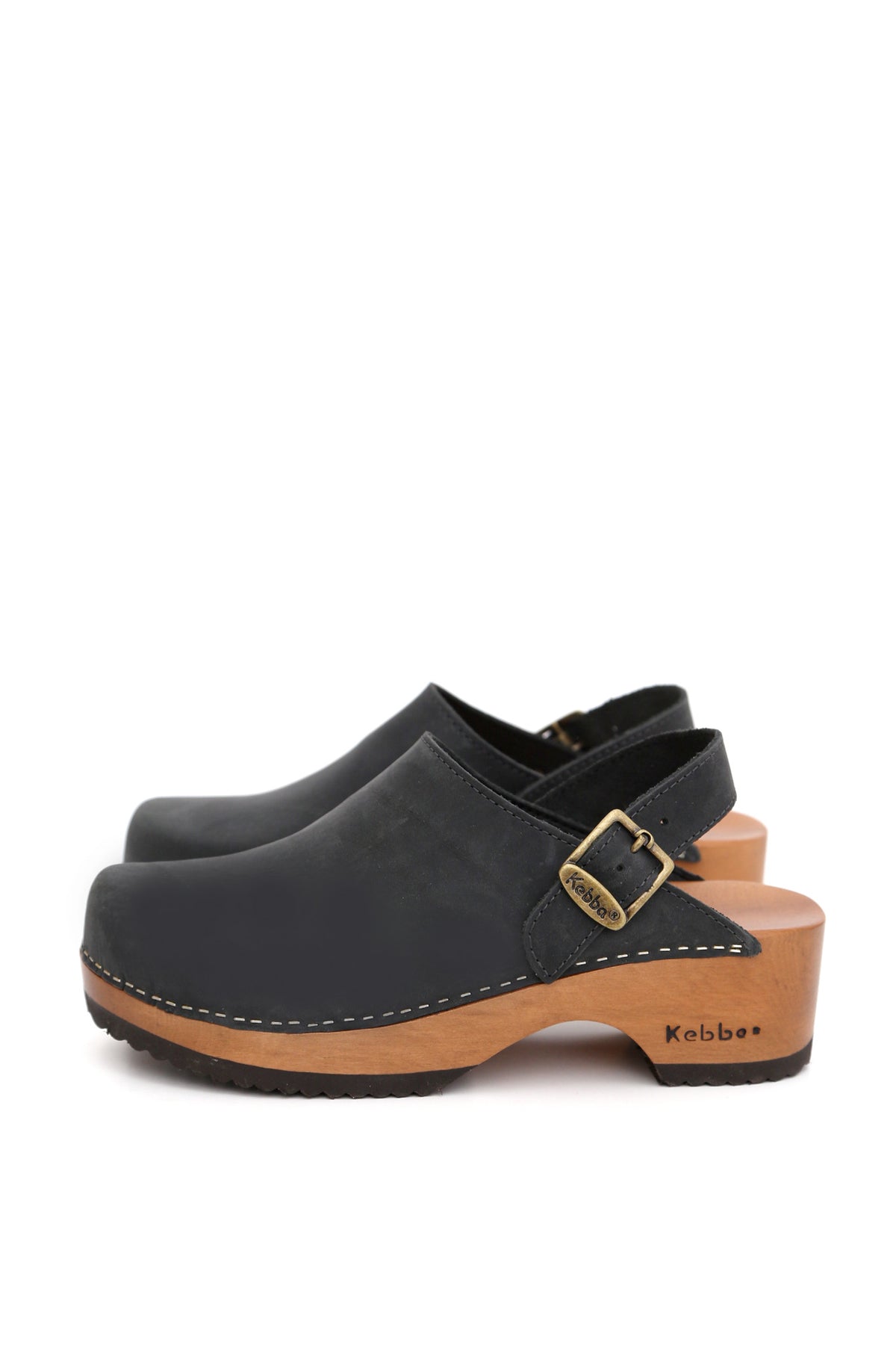 Zuecos artesanales Kebba negros de cuero natural y madera nativa con diseño anatómico, par sobre fondo blanco